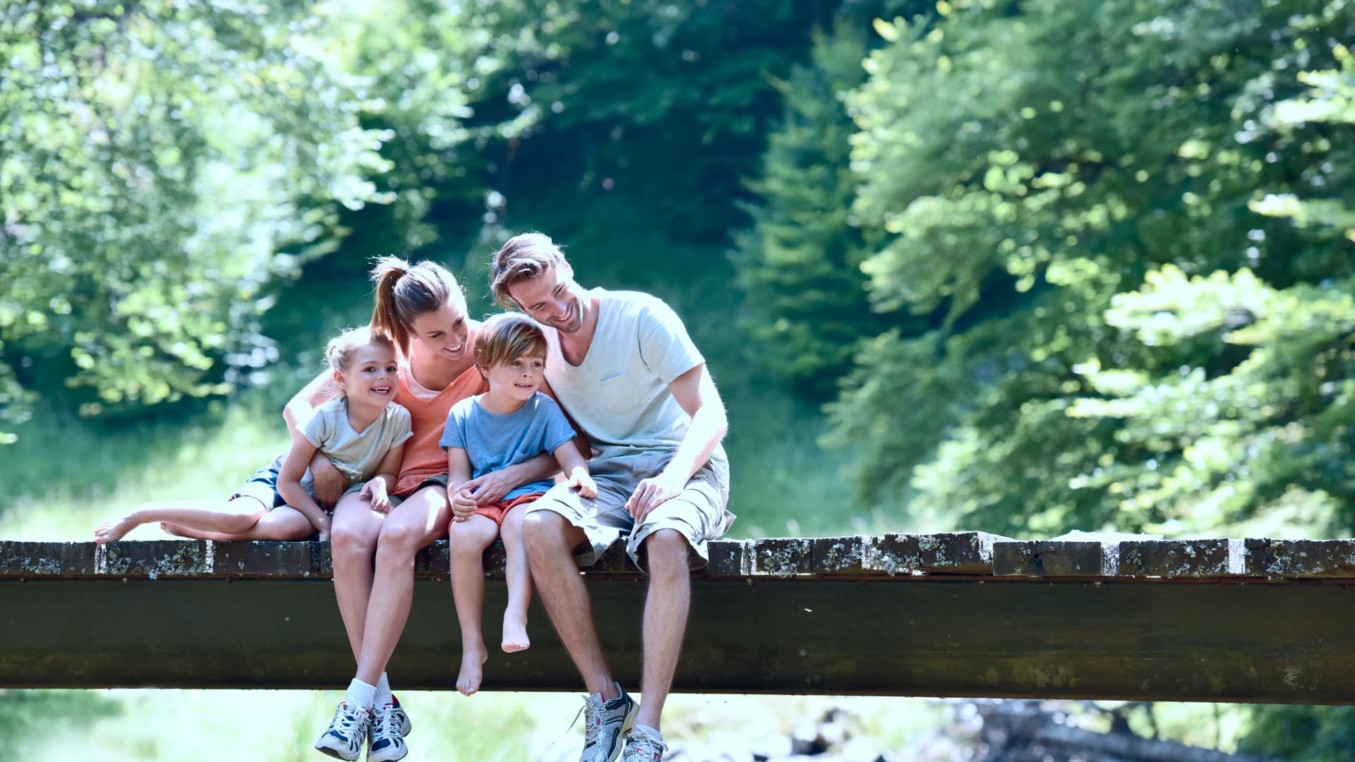 A family sitting together on a bridge, smiling.