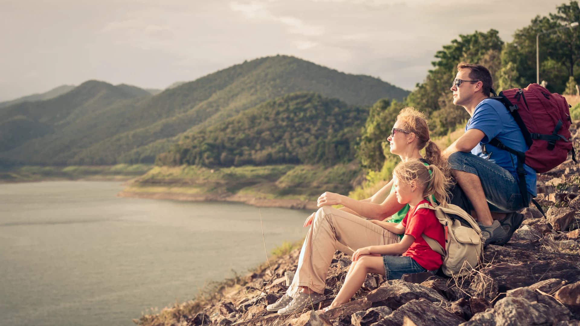 A family pausing on a hike to take in a mountain lake view.